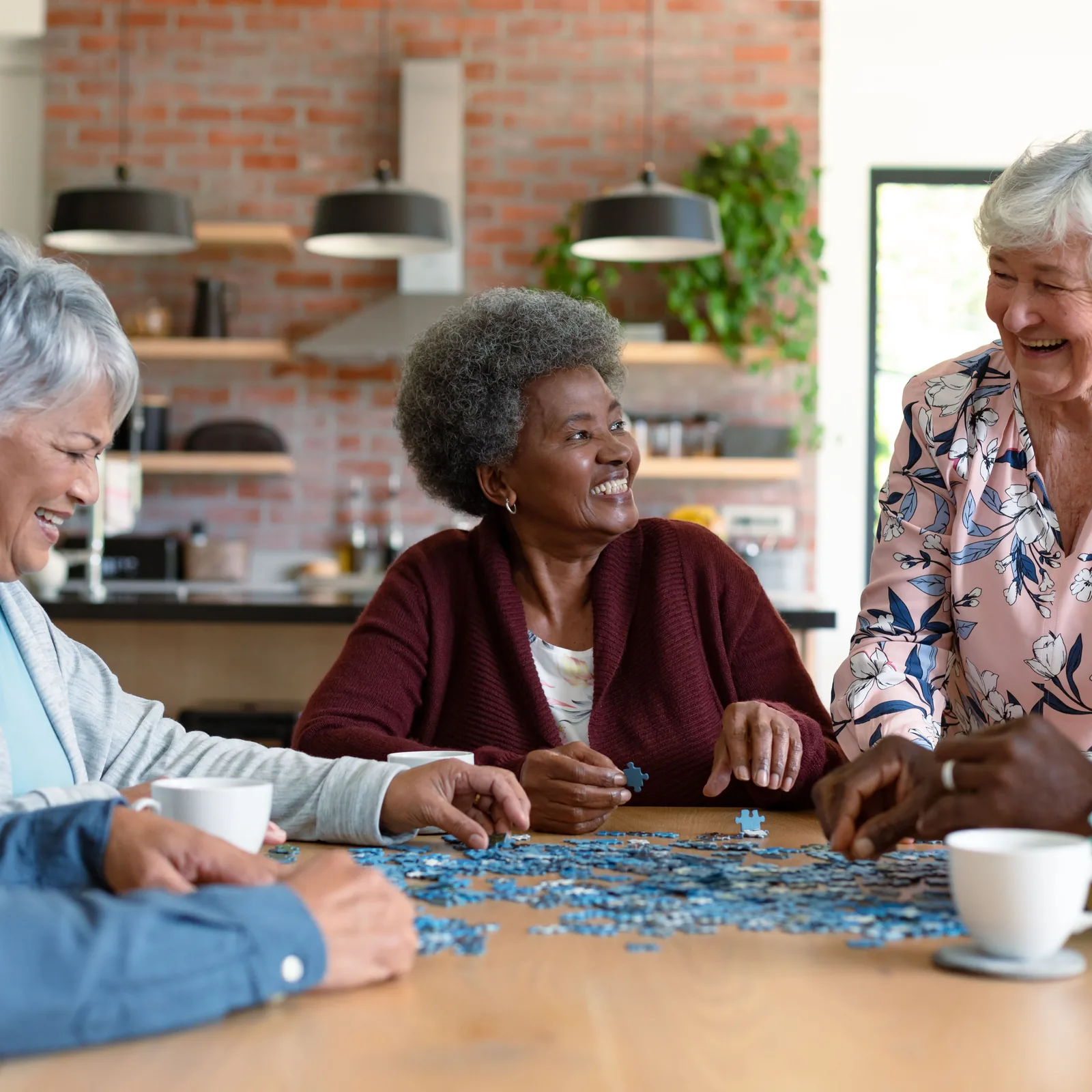 Older adults doing a jigsaw puzzle together at a kitchen table